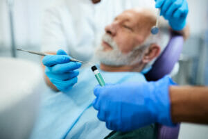 Close-up of dentist using dental filling while working on senior man's teeth.