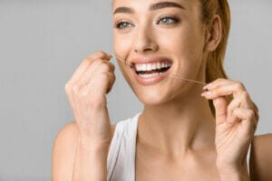 Tooth care. Young woman using dental floss
